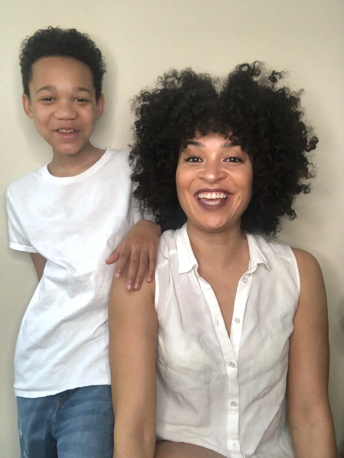 Mother seated with her young son standing up beside her