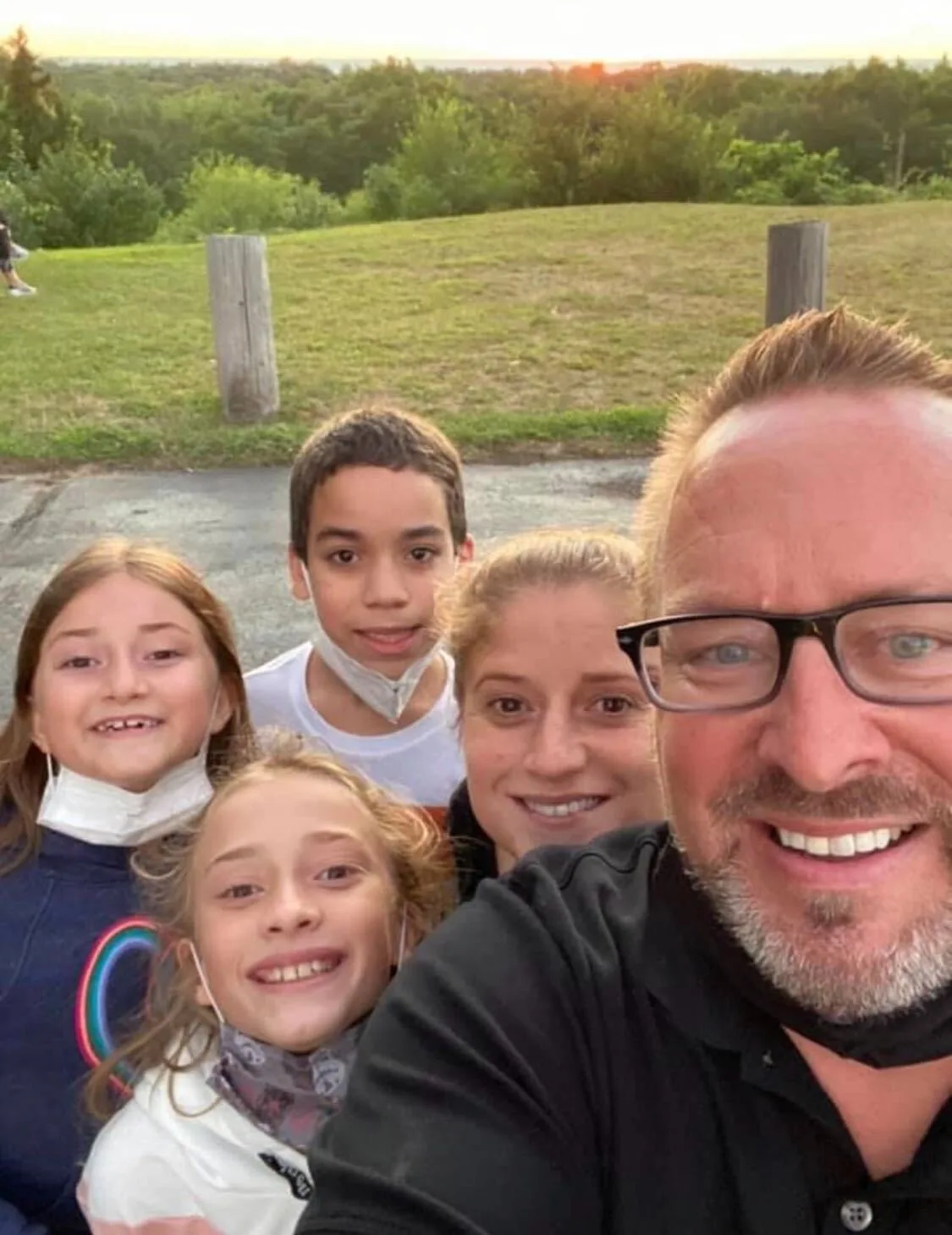 Two parents smiling with their three children standing behind them.