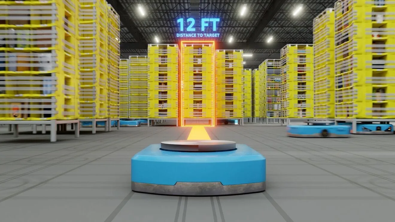 A robot’s point of view on an Amazon factory floor, with a lit up target (a stack of boxed products in the distance), a blue and silver rectangular robot in the foreground, and the text “12 FT DISTANCE TO TARGET” hovering over the target. Amazon’s DeepFleet coordinates robot movements across over 300 facilities worldwide, representing huge strides in the future of manufacturing.