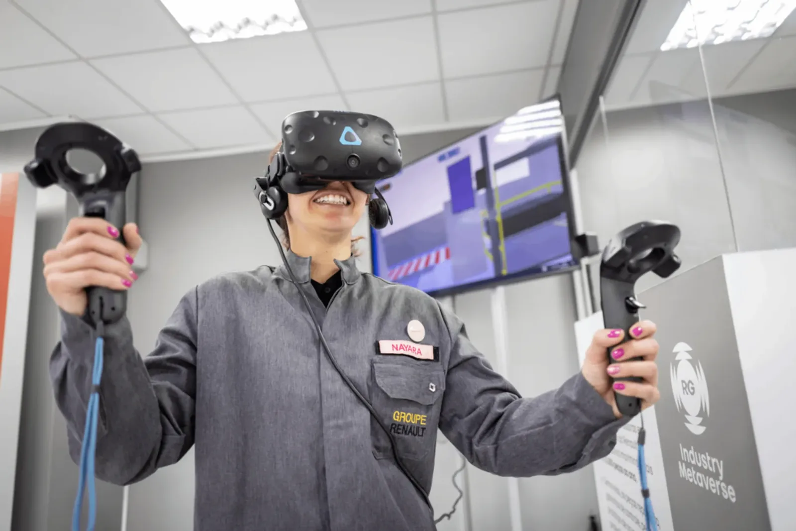 A Renault Group employee using a VR headset and controllers inside the Industry Metaverse facility, used for real-time digital twin simulation across manufacturing operations.