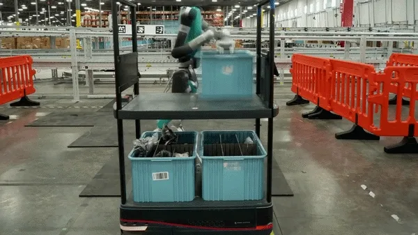 A gif shows a humanoid robot, Digit, at work at GXO’s Flowery Branch facility moving totes from rolling carts onto a conveyor belt. Physical AI applications like Digit are revolutionizing what is possible with AI and robotics.